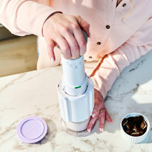 Cuisinart frozen treat maker with person placing a cup lid and spoon nearby