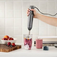 Immersion blender blending berry mixture in a tall glass cup