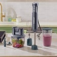 Immersion blender with blending shaft in a cup while processing ingredients