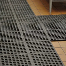 Interlocking floor mat tiles with circular holes, dark gray rubber, square layout