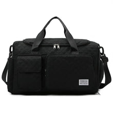 Black quilted travel duffel bag with padded top handle, front organizer pockets, and strap