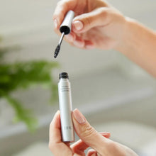 DHC glossy black mascara tube in hand with applicator wand