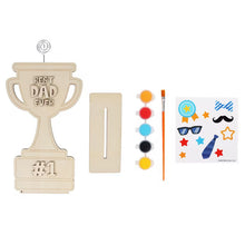 DIY trophy craft kit pieces: trophy cutout, paints, brush, and sticker sheet