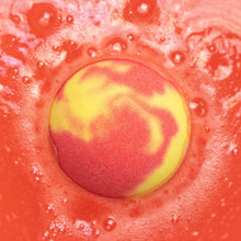 Close-up round bath fizzer with red outer and yellow-pink center swirl