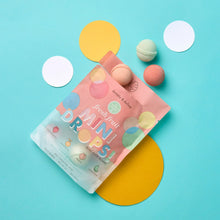 Mini bath bomb pouch with assorted fruit-scented mini bath bombs around it.