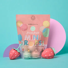 Mini bath bomb pouch with fruit-colored bath bombs placed in front.