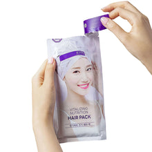 Hair pack sachet in purple and silver foil held in hands, standing upright