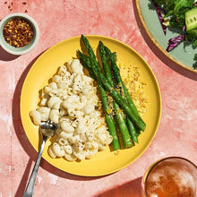 Creamy white macaroni with mac and cheese sauce and green asparagus on a plate