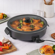 Gray electric ceramic skillet with lid, holding chicken pieces and broccoli florets