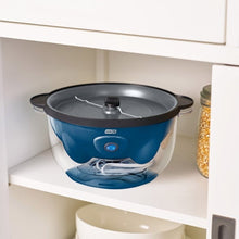 Blue popcorn maker stored on shelf with black lid and stirring paddle visible