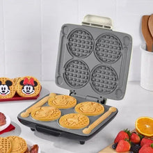 No-drip waffle maker open with four Mickey-shaped waffles on removable plate.