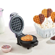Mini waffle maker opened with round waffle grid plate, ready for cooking.