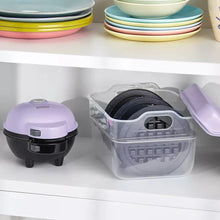 Mini waffle maker with lilac lid, black base, and clear plate storage container