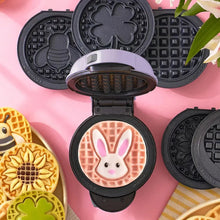 Mini waffle maker open to bake a pink bunny waffle on removable plates