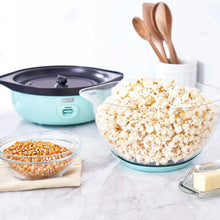 Light teal popcorn maker base with popping bowl, small glass bowl, and wooden spoons