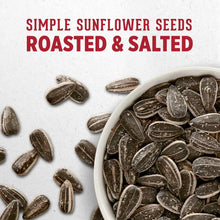 Roasted and salted sunflower seeds in a white bowl with scattered dark kernels