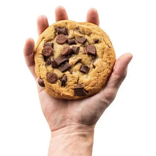 Hand holding a chocolate chip cookie with visible chocolate chunks