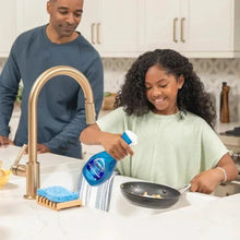 Dish soap spray bottle used at kitchen sink beside a frying pan