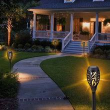 Solar tiki torch lights lining a walkway, with black stakes and gold flame-pattern lanterns