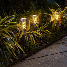 Glowing solar tiki torch lights with black poles and gold flame-pattern lantern heads