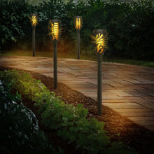 Four glowing solar tiki torch lights along a garden path with black stakes and gold lanterns