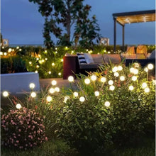 Warm white solar firefly lights glowing with round bulbs on garden stakes
