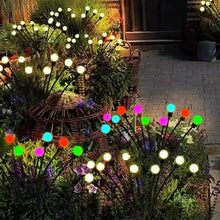 Multi-color solar firefly lights glowing on garden stakes with round globe bulbs