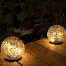 Glowing crackle glass LED globe lights with black bases on a wood deck