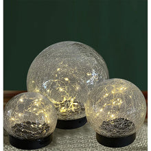 Crackle glass LED globe lights with black bases, three glowing globes