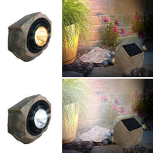 Solar rock landscape light in stone housing, lens emitting bright white and warm light