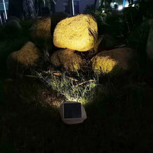Solar rock landscape lights in rocky garden, recessed lenses glowing under outdoor lighting
