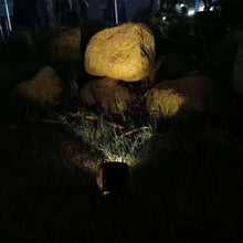 Solar rock lights in yard at night, dark stone housings with ground beams