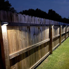 Solar deck lights along a fence line with warm white glow