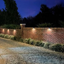 Solar wall deck light glowing warm white on a brick wall