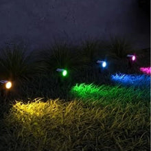 Garden solar spotlights glowing in multiple colors along grass and shrubs at night
