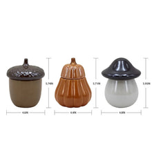 Three ceramic candle holders with lids in brown, orange, and dark gray