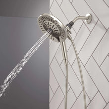 Hand shower with round spray head aimed forward, flexible hose and water spray