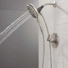 Overhead showerhead spraying water with handheld sprayer docked on wall mount
