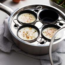 Stainless steel egg poacher set with four wells holding cooked eggs