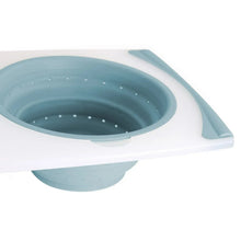 Blue-toned sink strainer bowl with perforated bottom on cutting board