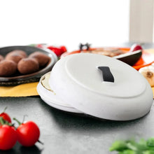 Tortilla warmer lid in white with black handle resting on a countertop