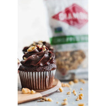 Cupcake topped with chopped walnuts, with a walnut bag blurred in the background
