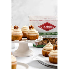 Shelled walnut kernels beside frosted cupcakes, with a shelled walnuts bag behind.