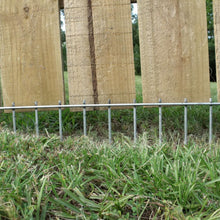 Metal animal barrier fence panel with vertical posts along yard grass