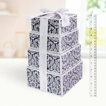 Stacked chocolate gift box in white and navy pattern with bow ribbon, beside ruler