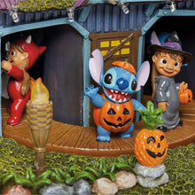 Halloween house display with elf-like figure, Stitch character, and glowing pumpkin props.