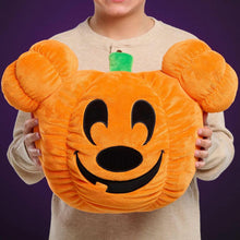 Orange Mickey pumpkin head plush held by child, green stem and black smile face