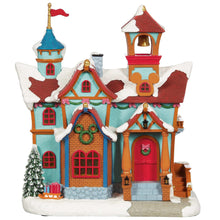 Disney holiday village house with turquoise walls, red doors, snow roof, and tower detail