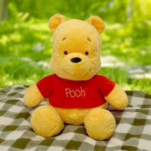 Winnie the Pooh plush toy in red shirt, relaxed sitting pose