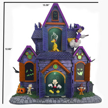 Halloween village decoration with purple haunted house, glowing window figures, and gray stone platform